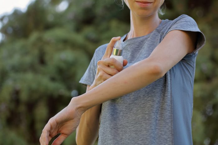 Mosquito repellent. Woman using insect repellent spray outdoors.