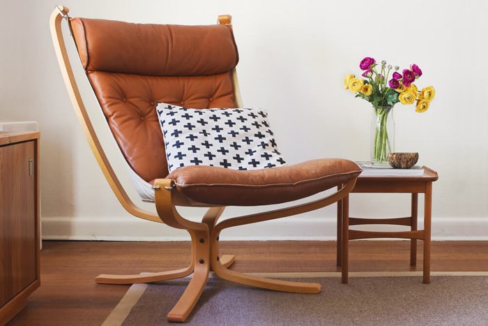 Retro tan leather chair and side table with flowers interior