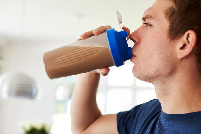 Man Drinking Protein Shake In Kitchen At Home