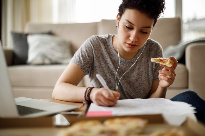 female student studying and eating pizza