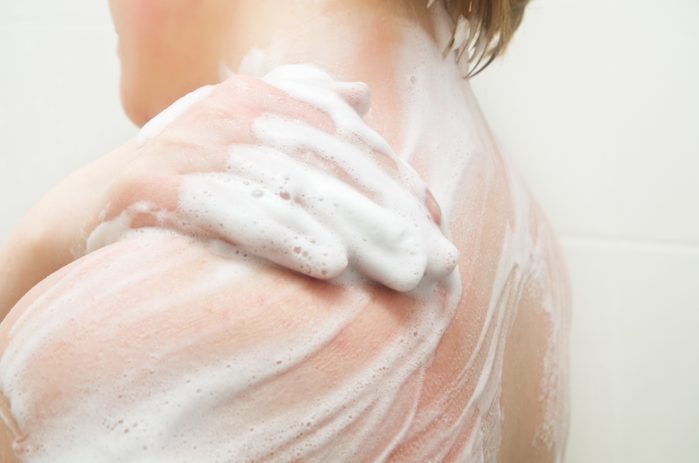 close up of woman applying soap to body in shower