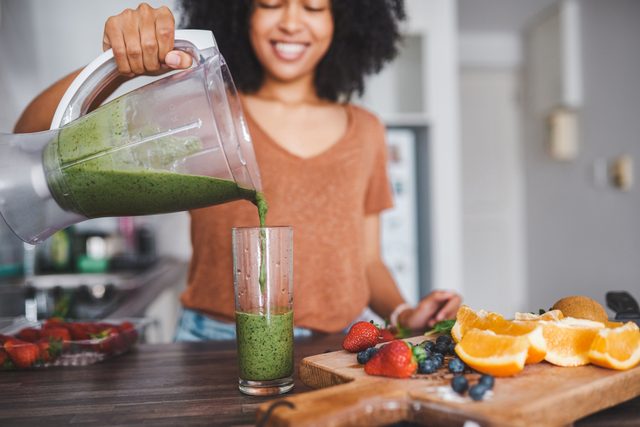 woman pouring healthy smoothie into glass