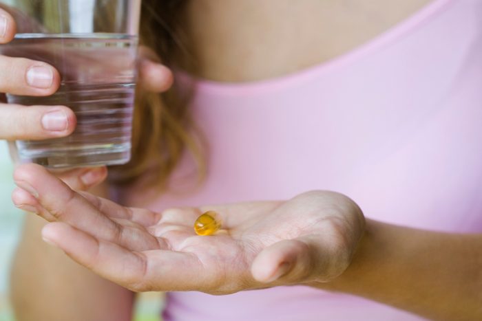 woman holding vitamin and glass of water