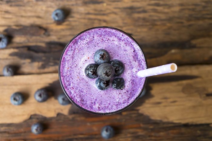 Blueberry smoothie in a glass, topped with fresh blueberries