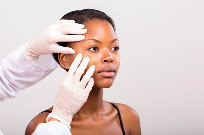 dermatologist checking the skin on a young woman's face 