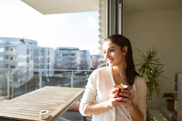smiling woman on balcony holding mug