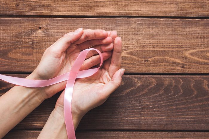 pink ribbon twisted into breast cancer symbol in cupped hands