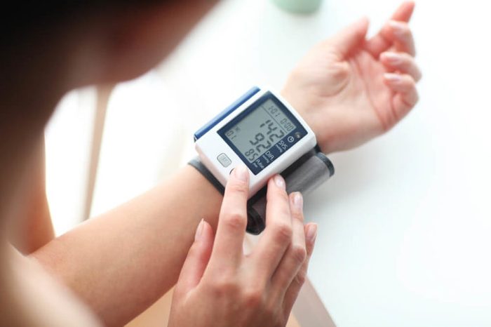 Person with digital blood pressure monitor on wrist