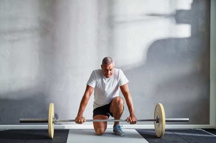 Man kneeling down to pick up a barbell with large weights
