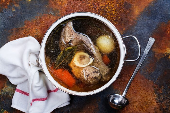 Broth soup in a cooking pot with ladle