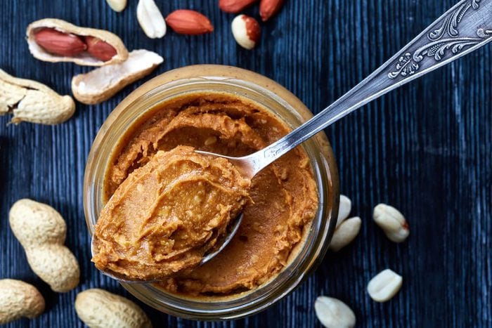 Jar and spoon of peanut butter and peanuts