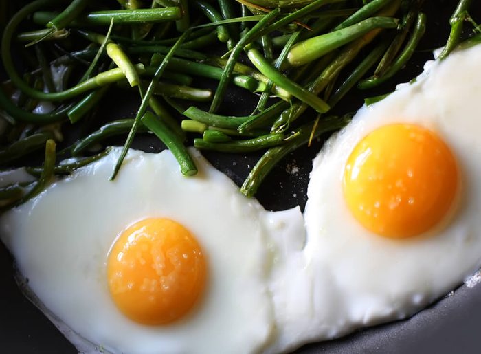 Fried eggs with green beans on the pan