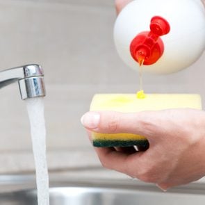 woman hand holding yellow sponge and pouring cleaning liquid on it