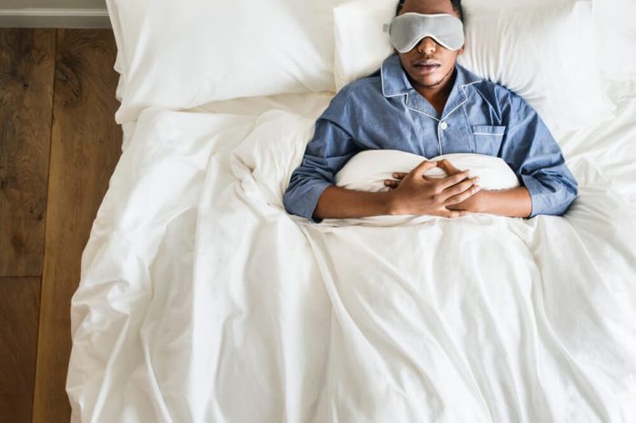 Man sleeping on bed with eye mask.