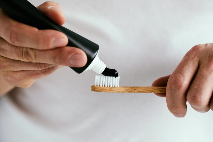 Man with a black charcoal toothpaste and a bamboo toothbrush.
