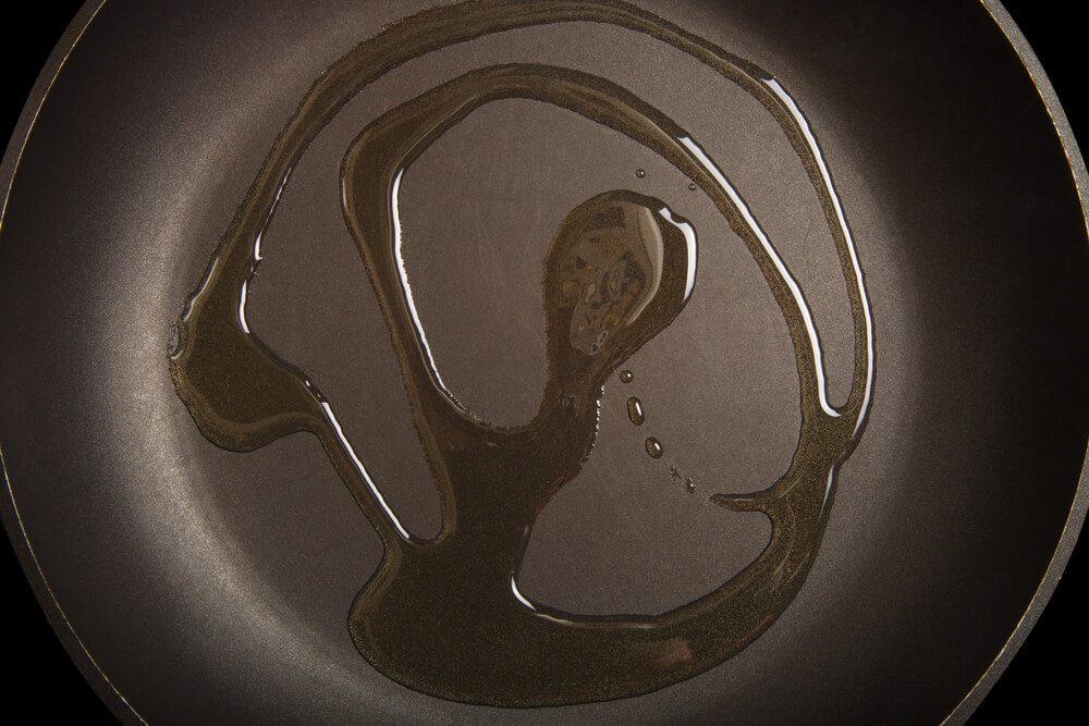 Olive oil on black frying pan. Toned.