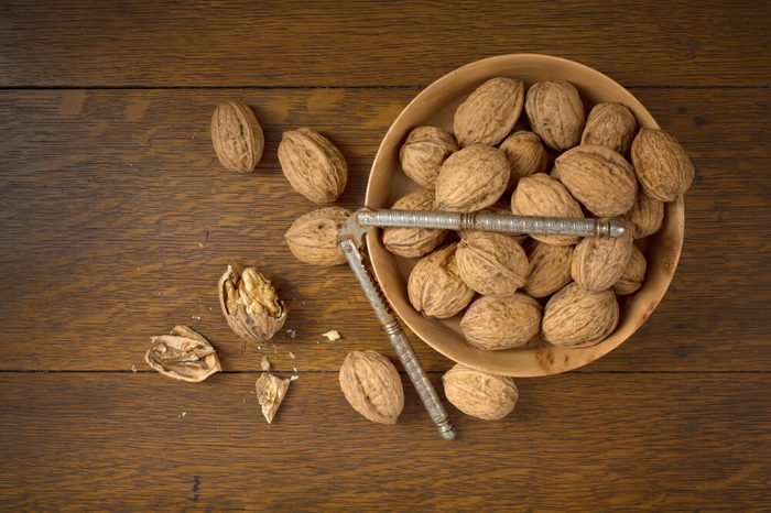 Bowl of walnuts, nut cracker, one opened walnut