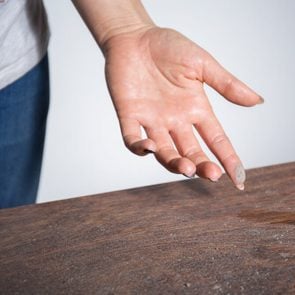 Close-up of dust on woman finger taken from wooden table