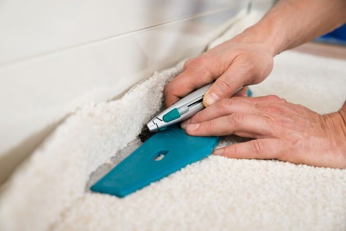 Close-up Of A Craftsman Cutting Carpet With Cutter