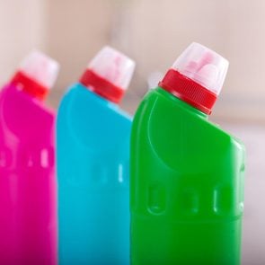 Close up of group of colorful cleaning supplies with tiled wall in background. House keeping and hygiene concept