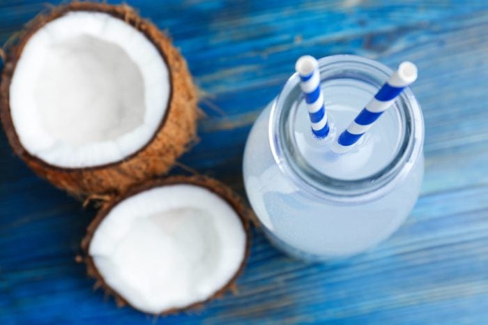 Bottle of coconut water with fresh nuts on wooden background