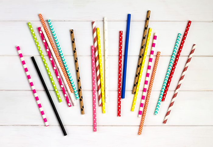 Colorful paper straws on white wooden background. Event and party supplies.