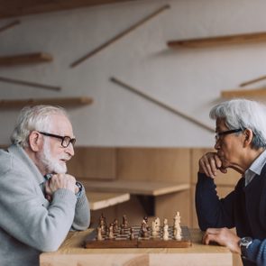 side view of multiethnic senior men playing chess