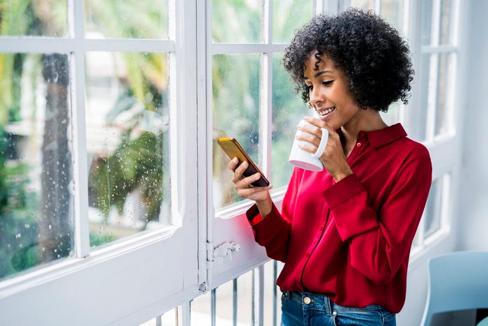 woman drinking a cup of coffee and looking at phone