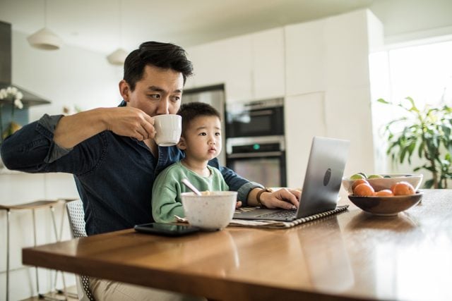 father working at home with son in lap