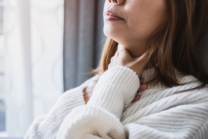 cropped shot of woman holding sore throat