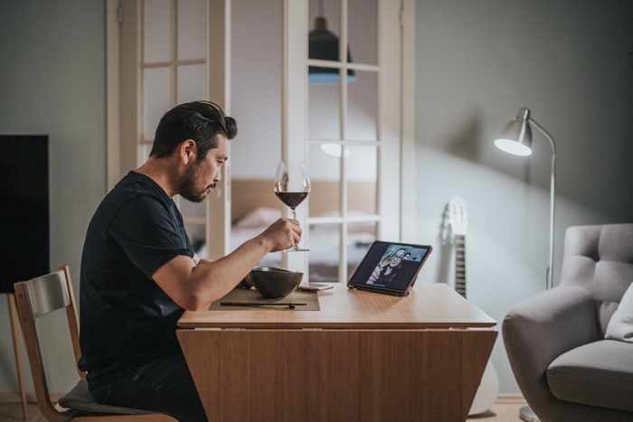man drinking wine during virtual dinner date at home