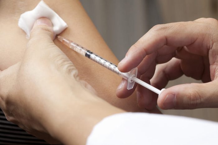 doctor injecting needle into patient's arm