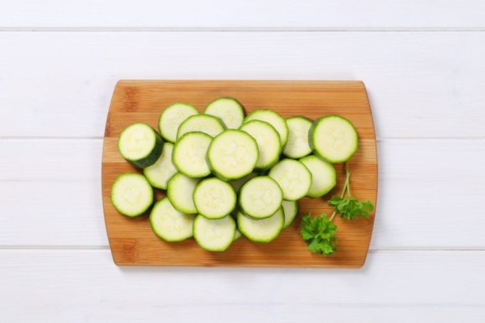 pile of green zucchini slices on wooden cutting board
