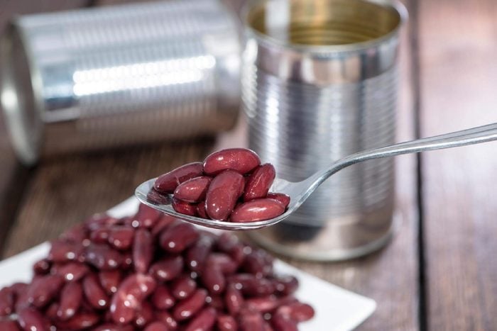 Kidney beans on a Spoon with blurred cans in the background