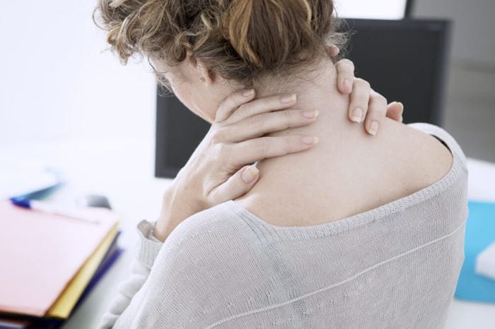 Woman holding her neck at the office.