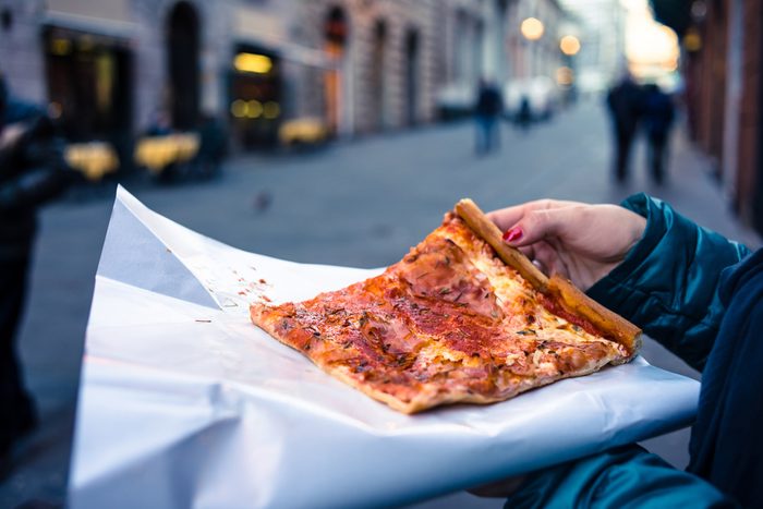 woman holding a square slice of pizza 