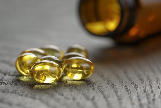 fish oil capsules with bottle on wooden table