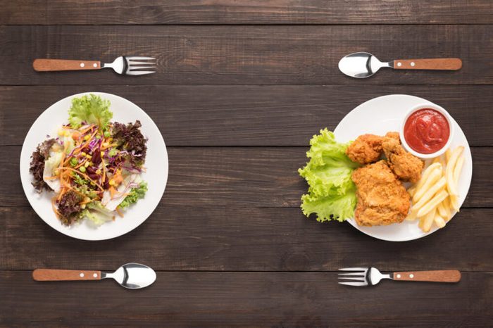 two plates: one with salad and one with fried chicken with French fries