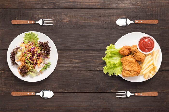 two plates: one with salad and one with fried chicken with French fries