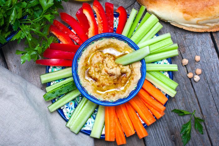 Homemade hummus with sliced celery, carrots, and red bell peppers