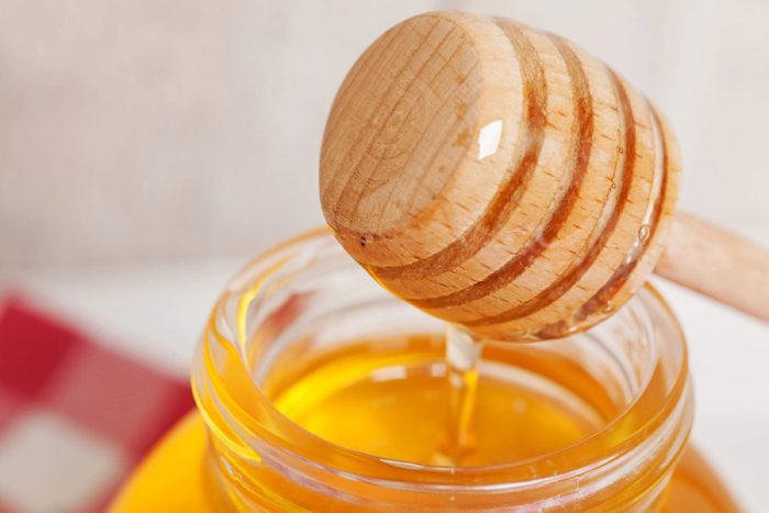 Jar of honey with wooden honey dipper. 
