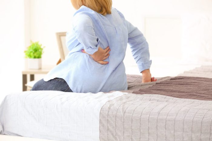 Woman suffering from backache at home.