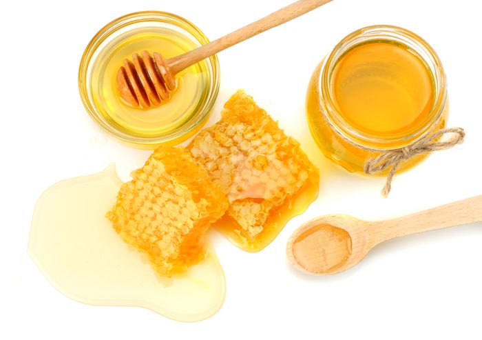 Honeycomb with honey dipper and honey isolated on white background. top view