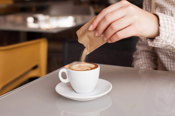 Woman adding sugar in coffee