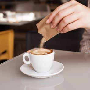Woman hand adding sugar in coffee