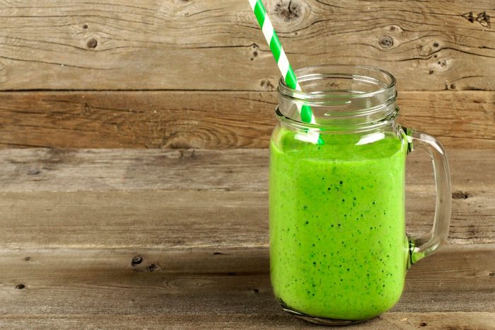 green smoothing with straw in jar-like glass with handle
