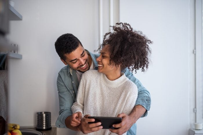 Happy african american couple using a tablet in the kitchen.