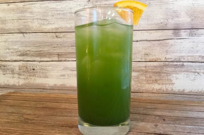 green drink in a tall glass with a orange wedge