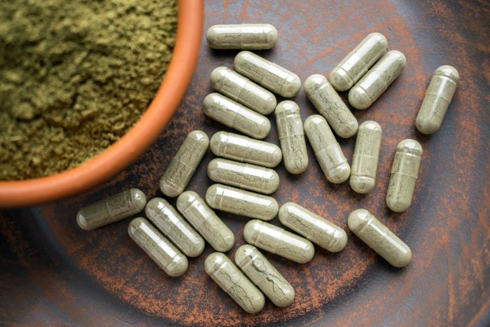 Bowl of green powder surrounded by green capsules