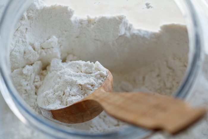 flour in jar with wooden spoon from above